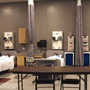 Training mannequins lie in medical beds in a CNA training room.